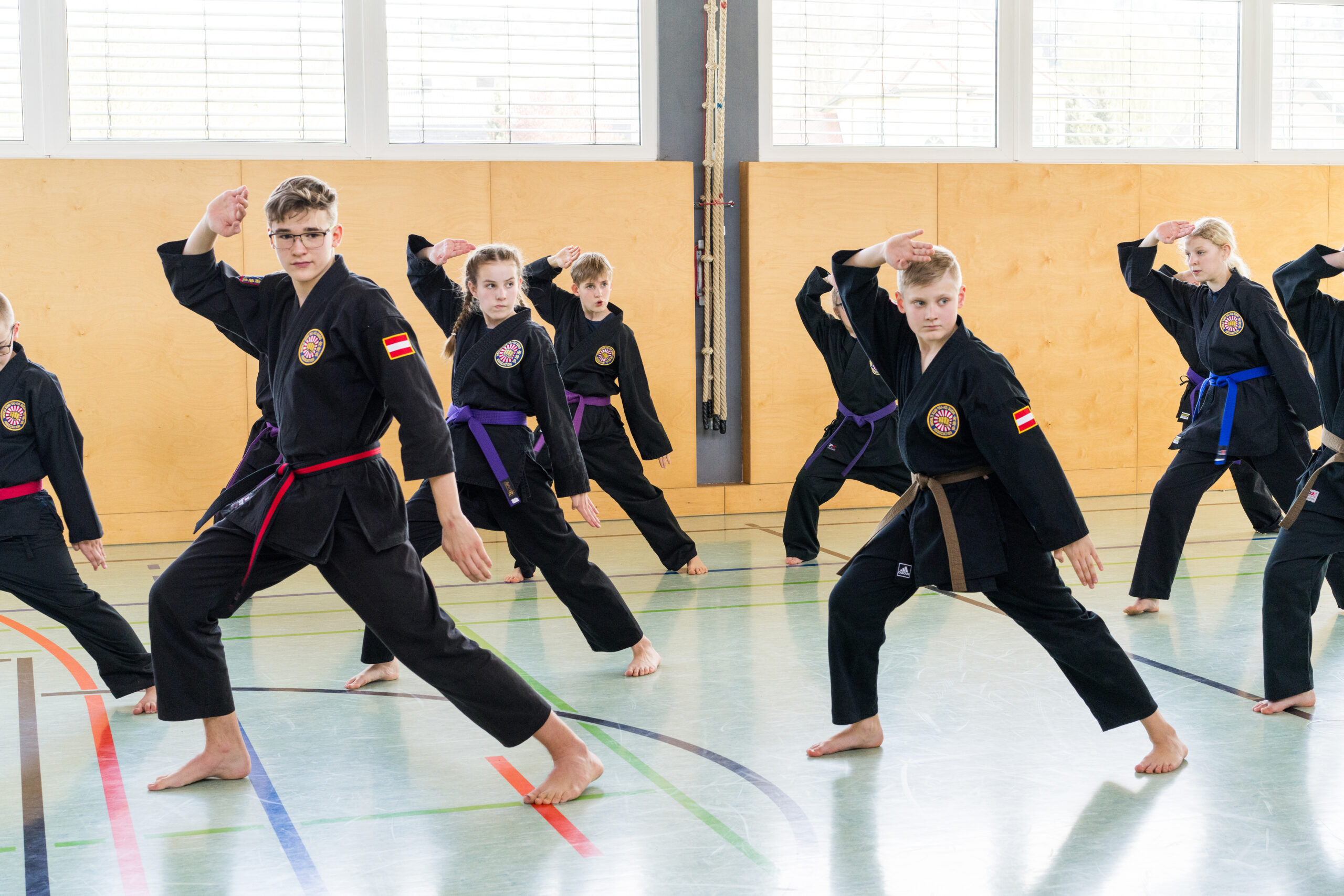 Eifrige Karateschüler perfektionieren Techniken gemeinsam in einer Turnhalle.