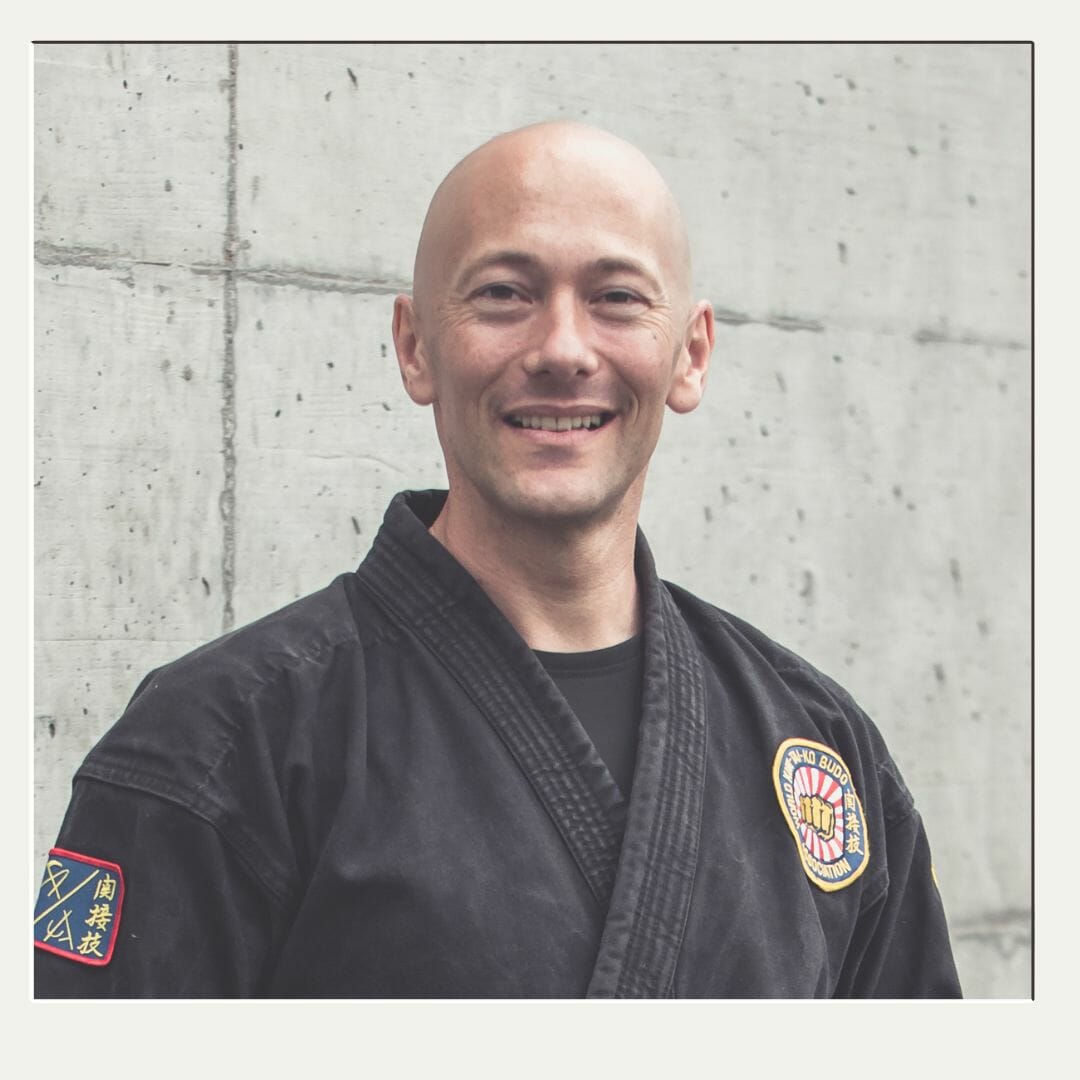 Selbstbewusster Karatelehrer lächelt im Karateanzug für sein Portrait.