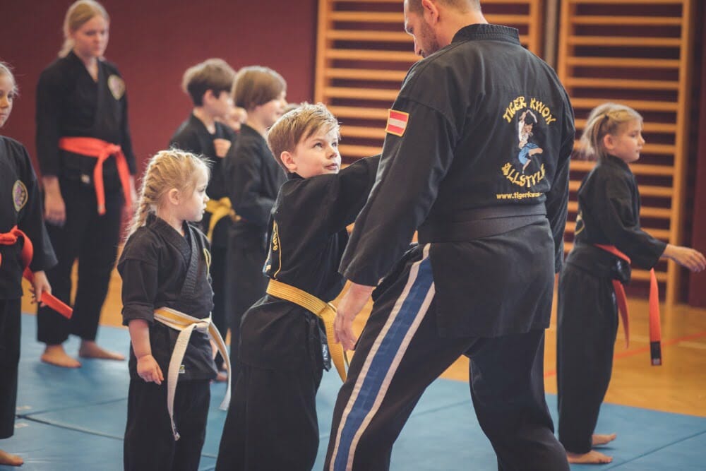 Karateschüler gewinnt Selbstvertrauen durch Selbstbehauptungsübung mit seinem Lehrer im Unterricht.