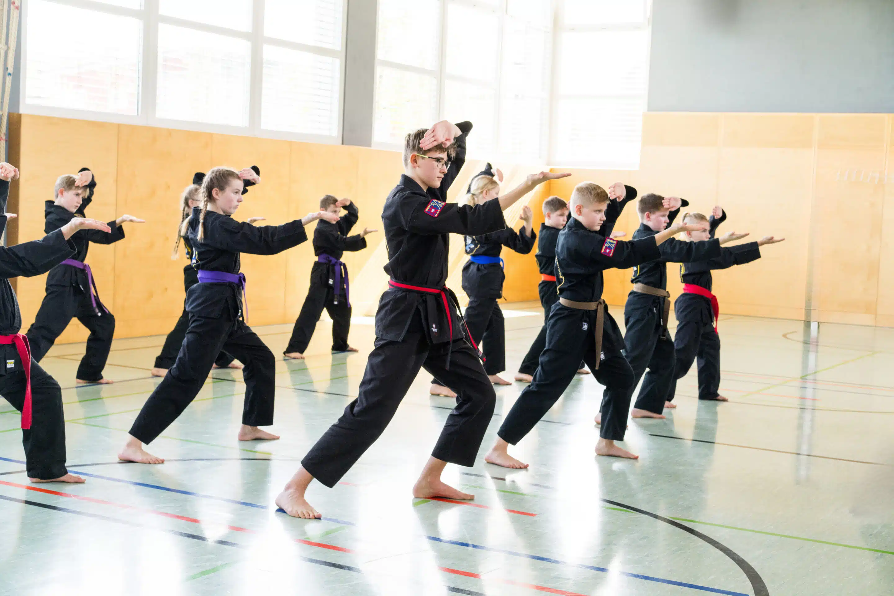 Eifrige Karateschüler perfektionieren Techniken gemeinsam in einer Turnhalle. Kinder Karate