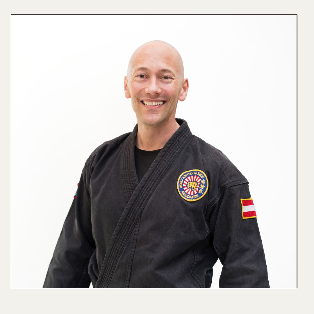Peter 2024 Selbstbewusster Karatelehrer lächelt im Karateanzug für sein Portrait.